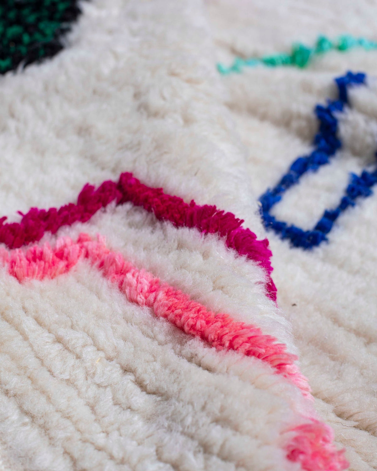 Texture ravvicinata del tappeto bianco con segni fucsia, verde acqua e blu
