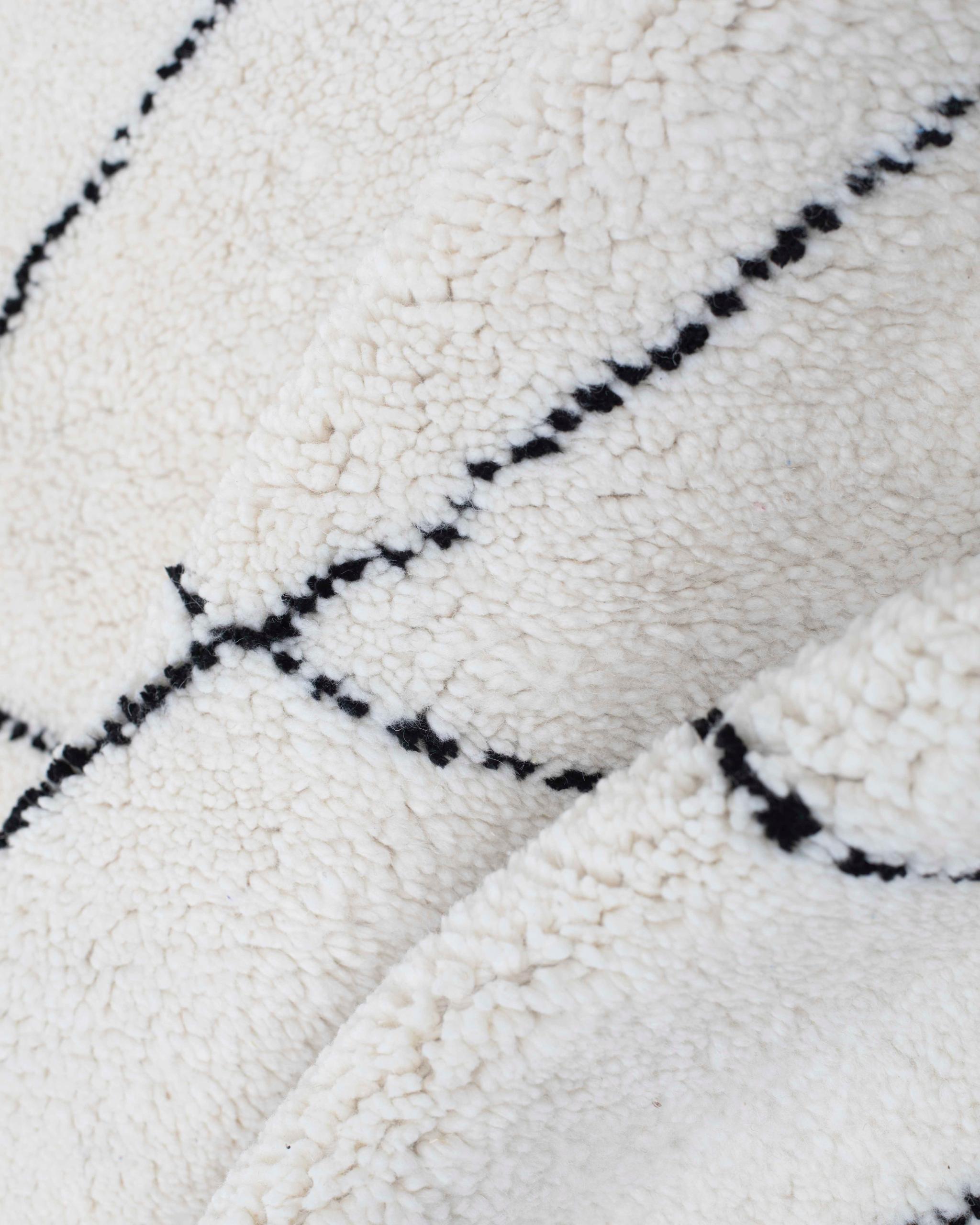 Texture ravvicinata della lana bianca e delle linee nere del tappeto Beni Ourain annodato a mano