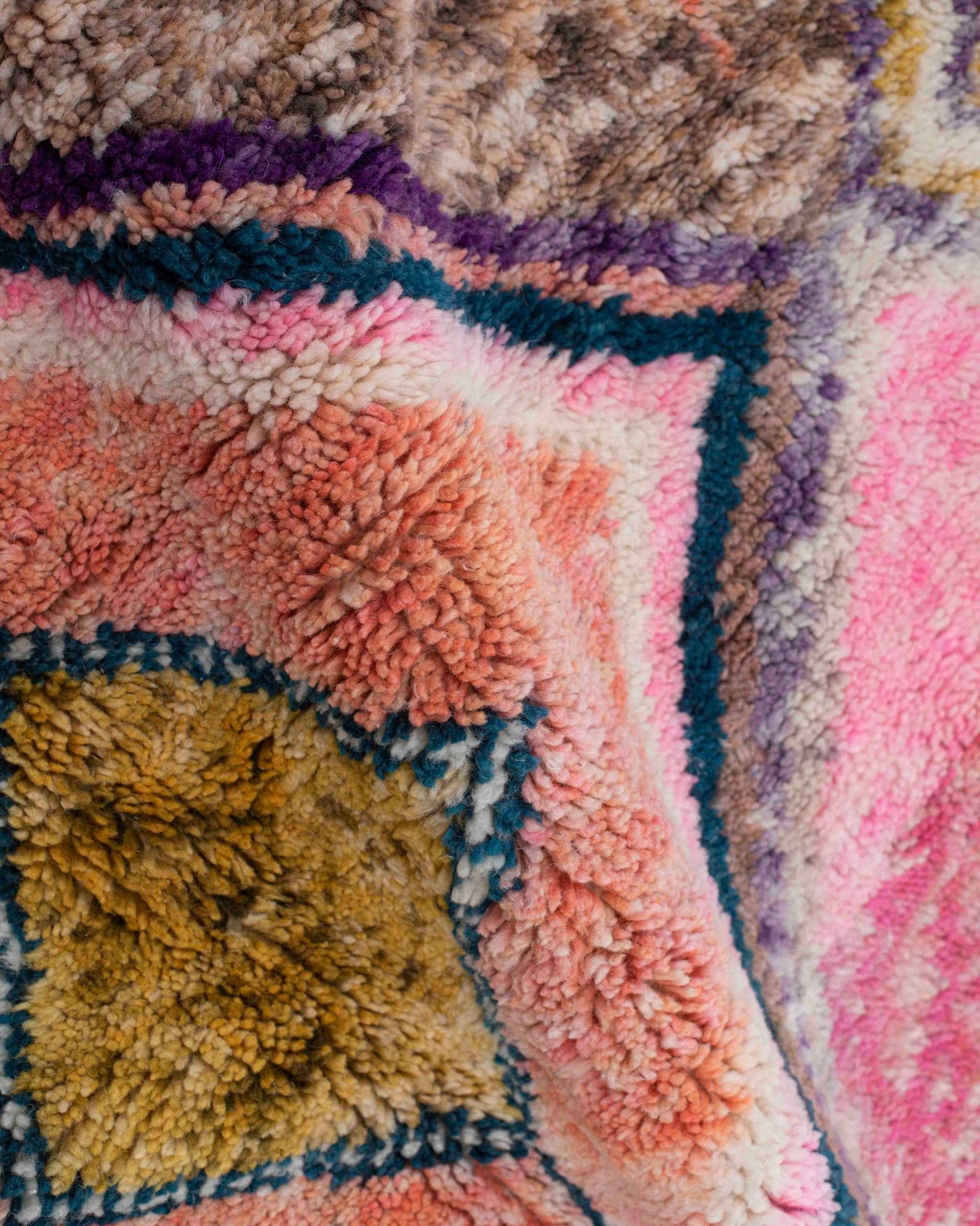 Texture ravvicinata della lana con rombi ocra, rosa, viola e marroni del tappeto Beni Ourain multicolore