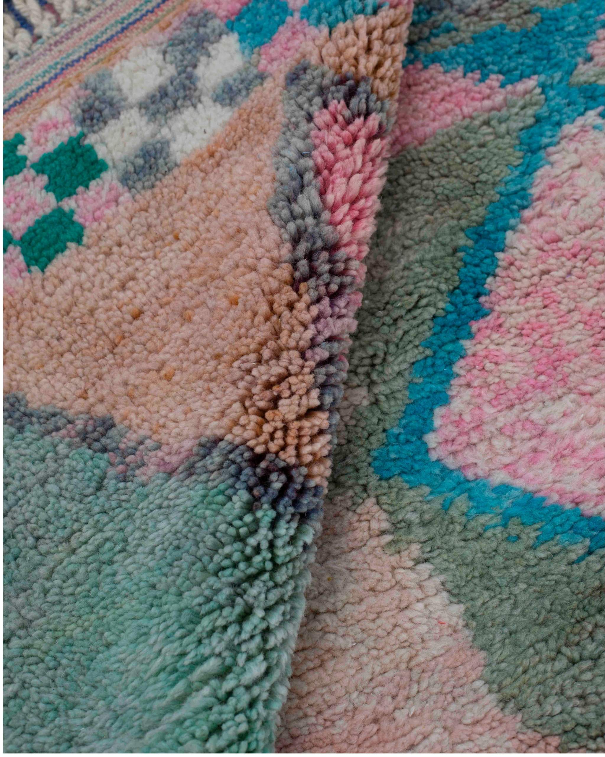 Texture ravvicinata della lana verde, rosa e turchese del tappeto berbero Beni Ourain con motivi geometrici e figurativi
