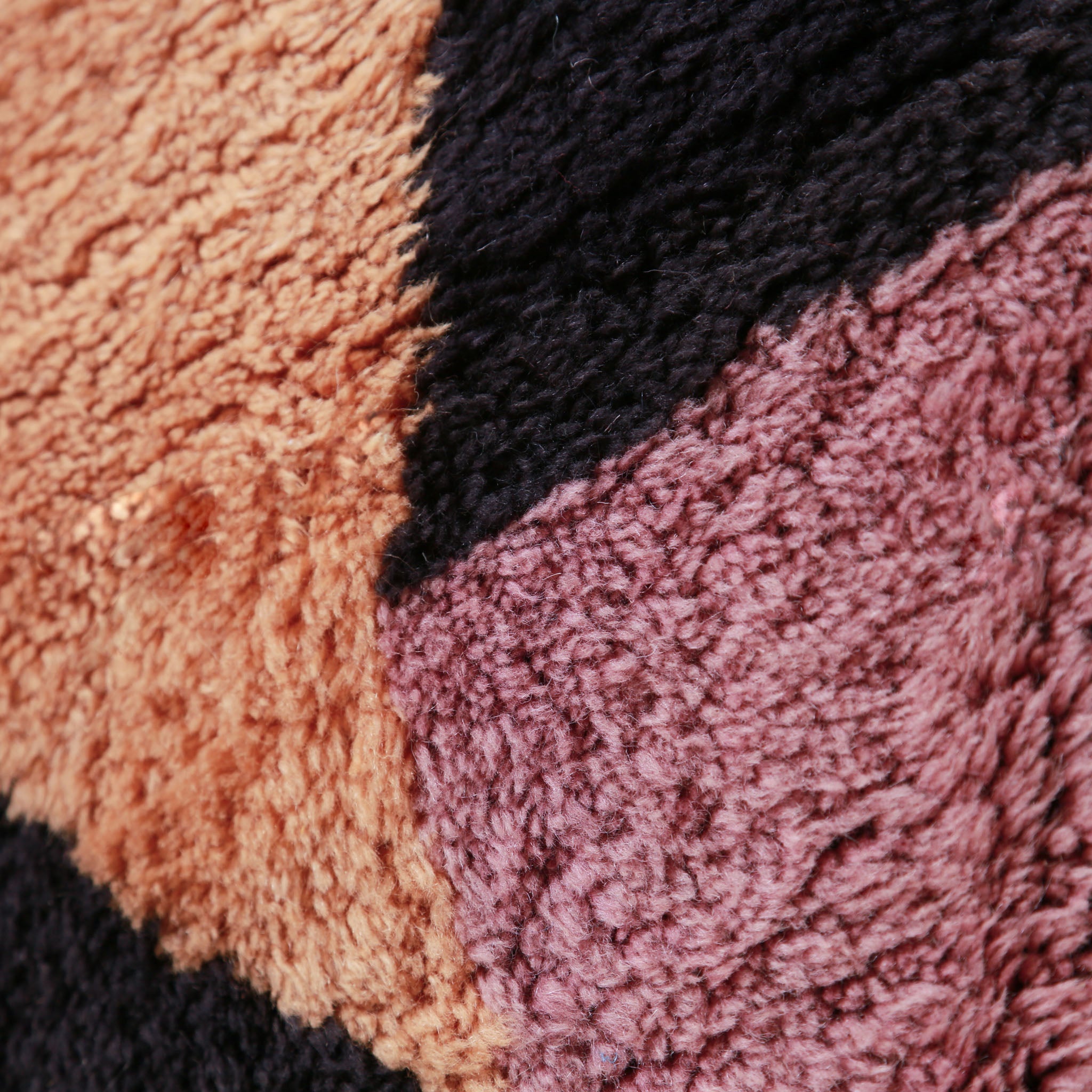 Texture del pelo di un tappeto berbero marocchino Beni M'rirt. Primo piano che mostra la lana spessa e morbida in colori arancione, nero e rosa. Evidenzia la qualità artigianale del tappeto.