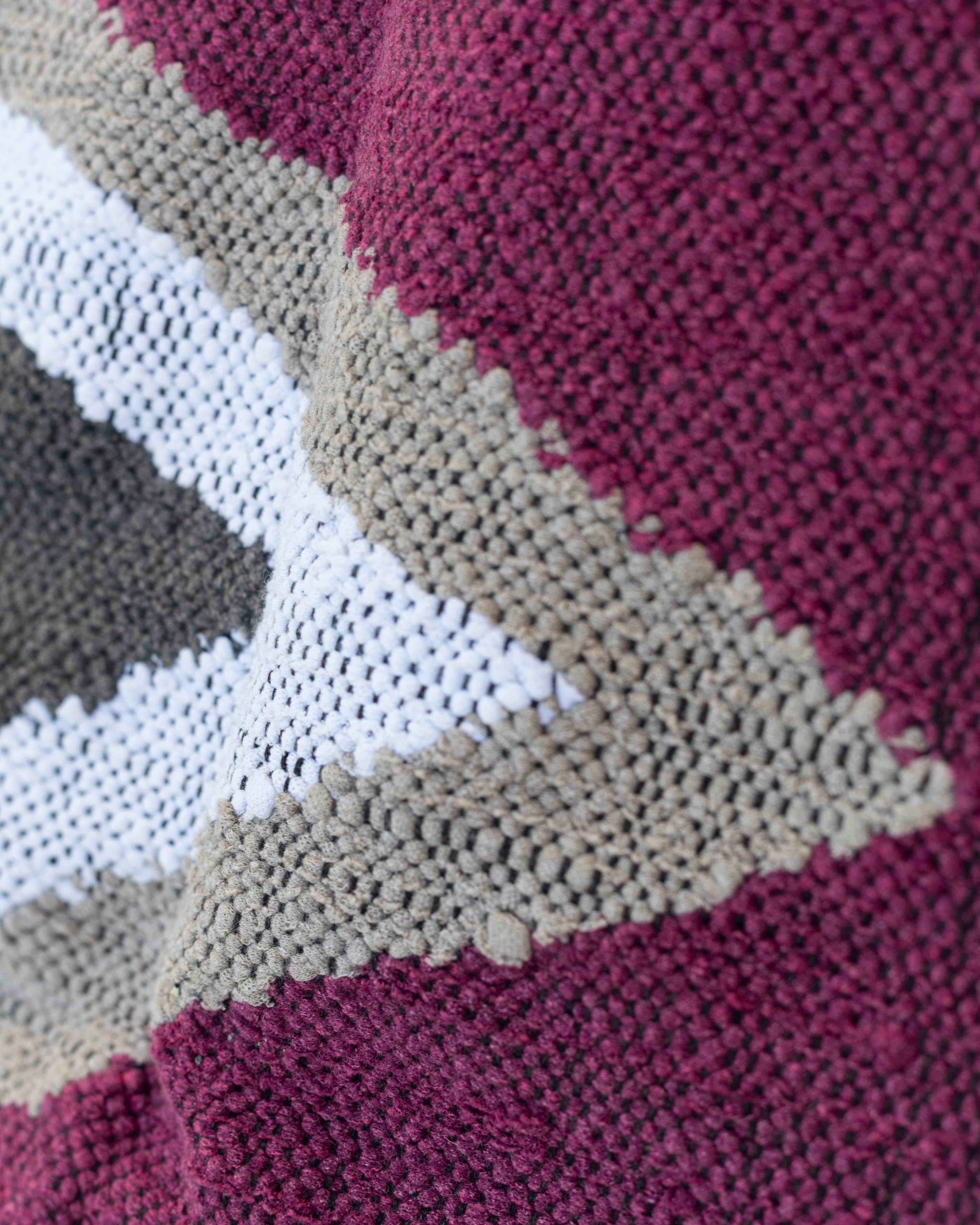 Texture ravvicinata del tappeto boucherouite con campiture viola-magenta, bianco e grigio