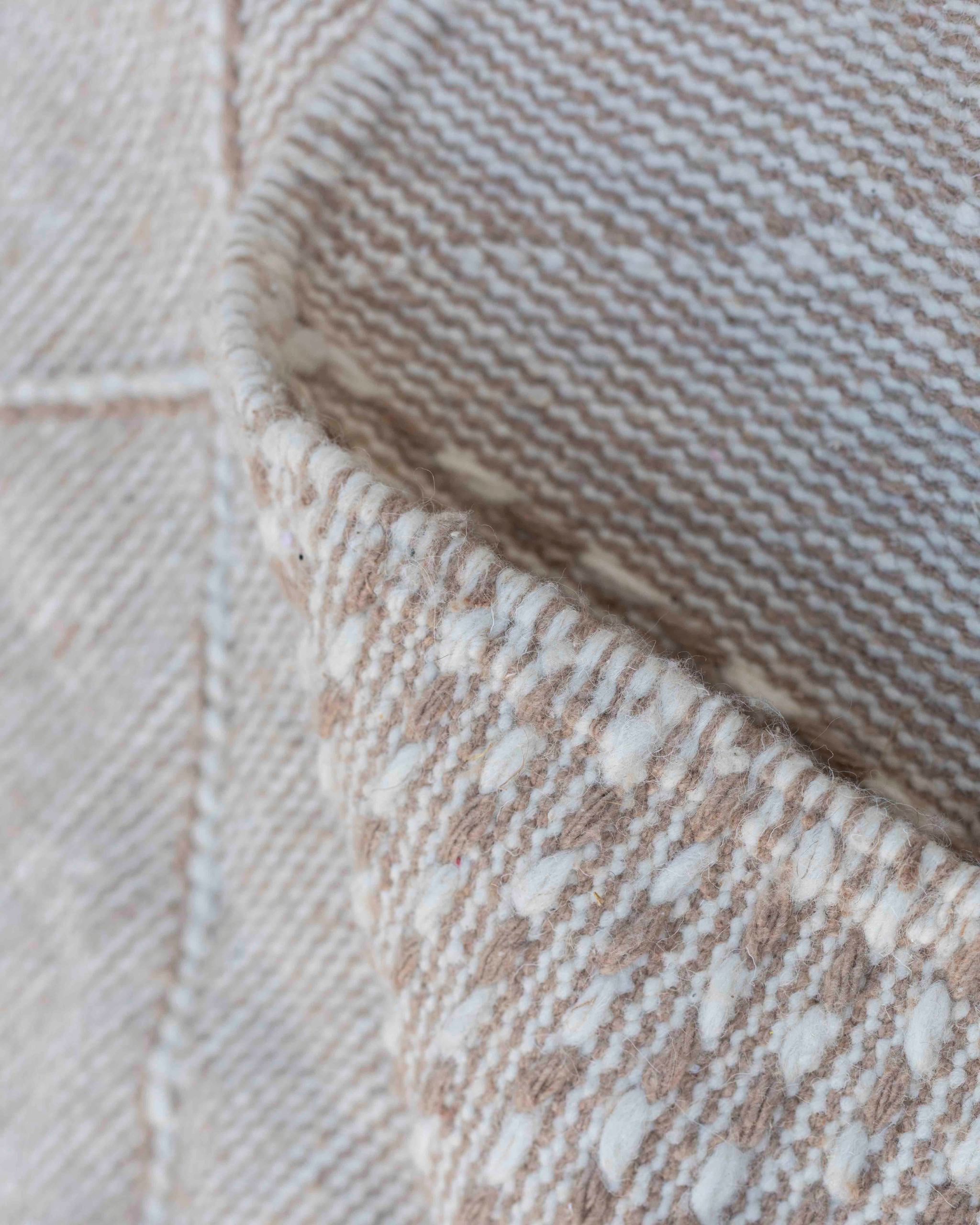 Dettaglio texture e cimosa del tappeto kilim in lana beige e avorio