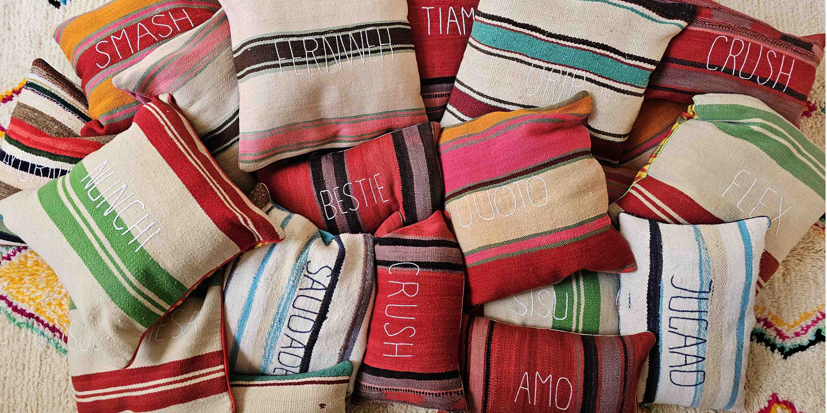 cuscini di diversi colori della collezione tra le righe raggruppati su un tappeto
