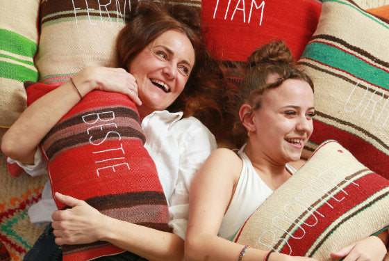 sabina maffei plozner e sua figlia costanza abbracciano due cuscini della collezione tra le righe distese su dei cuscini