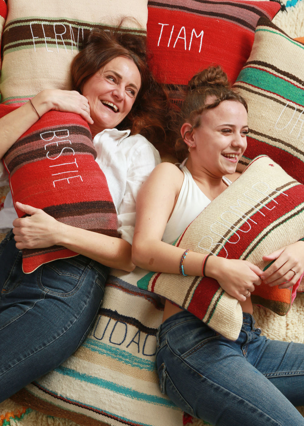 sabina maffei plozner e sua figlia costanza ridono sdraite su un tappeto pieno di cuscini mentre abbracciano un cuscino della collezione tra le righe