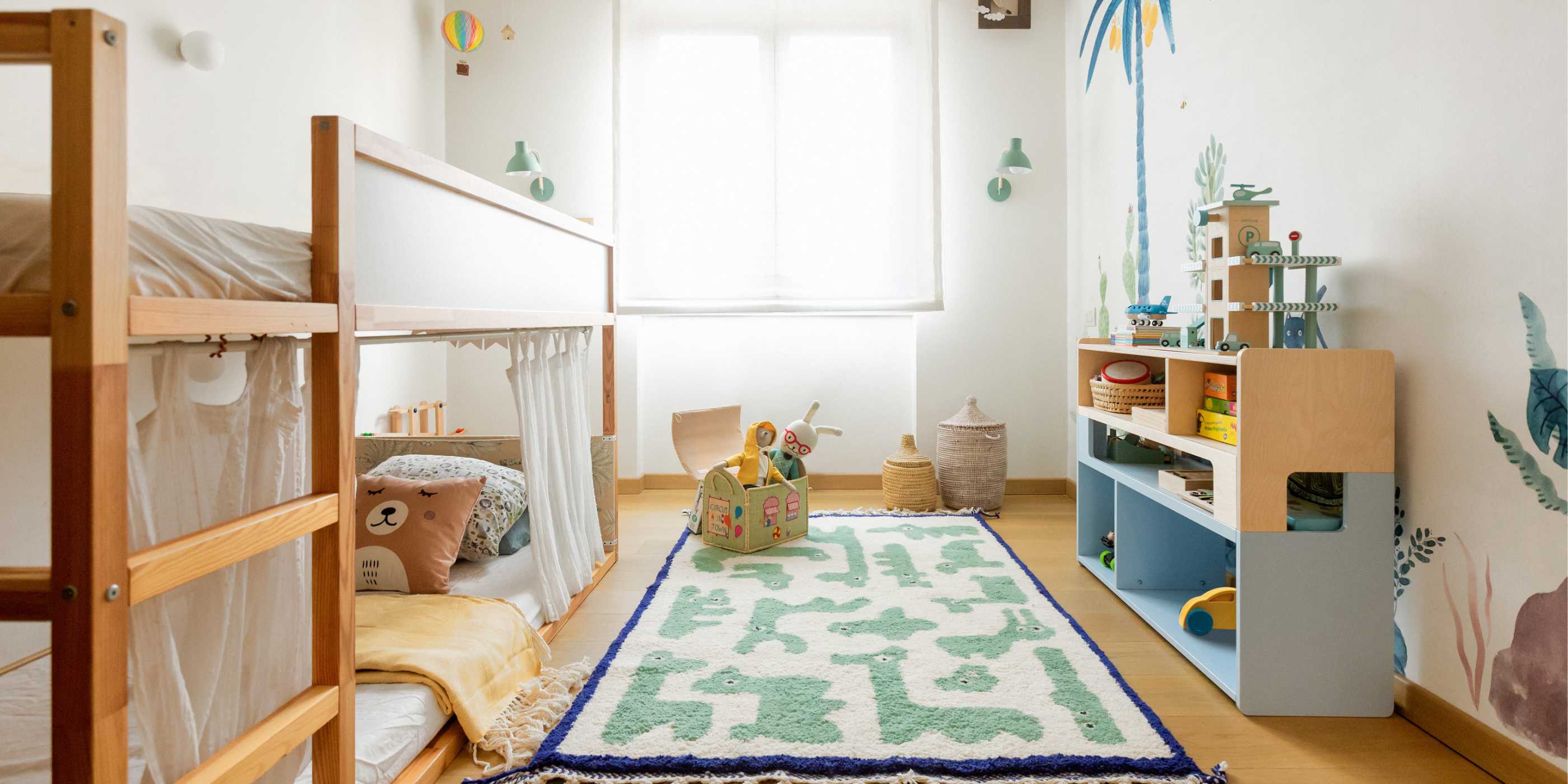 Cameretta montessoriana con tappeto Animauì verde in lana marocchina, letto a baldacchino in legno e decorazioni murali tropicali, arredo sostenibile e naturale