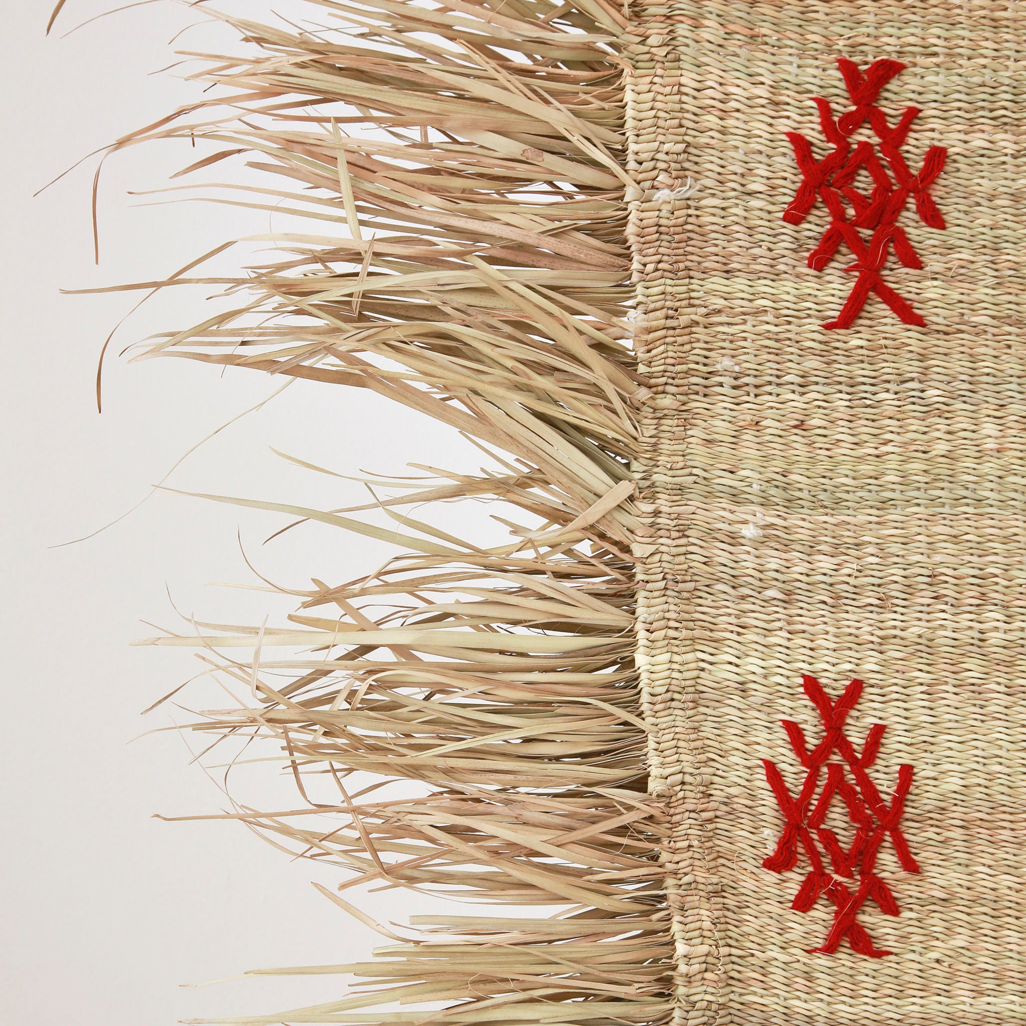 dettaglio della frangia di una piccola stuoia hassira intrecciata con paglia di palma e ricamata con simboli in lana rossa