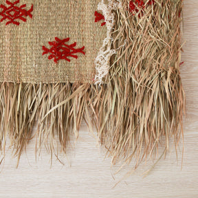 dettaglio del retro di una piccola stuoia hassira intrecciata con paglia di palma e ricamata con simboli in lana rossa