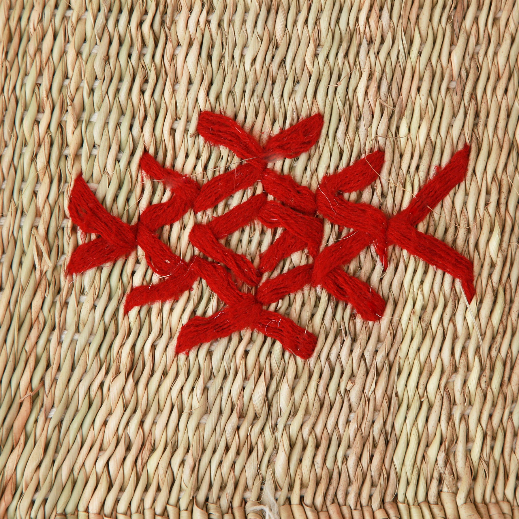 dettaglio del simbolo di una piccola stuoia hassira intrecciata con paglia di palma e ricamata con simboli in lana rossa
