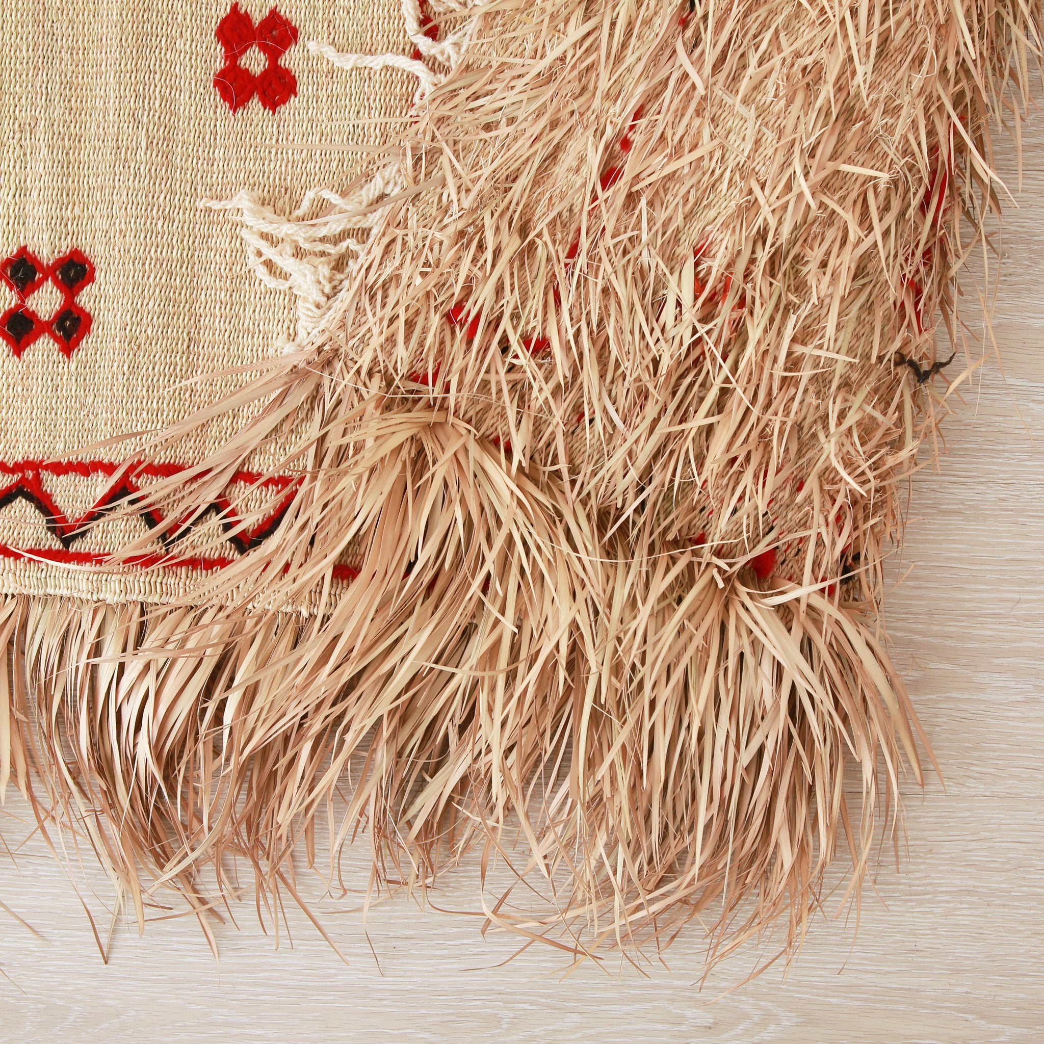 dettaglio del retro di una stuoia hassira intrecciata a mano con paglia di palma e ricamata con con lana rossa e nera.