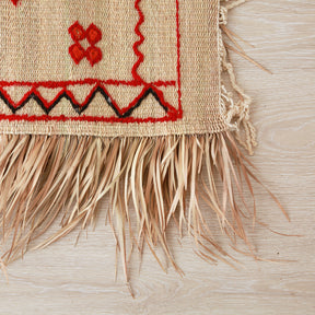 dettaglio dell'angolo di una stuoia hassira intrecciata a mano con paglia di palma e ricamata con con lana rossa e nera.