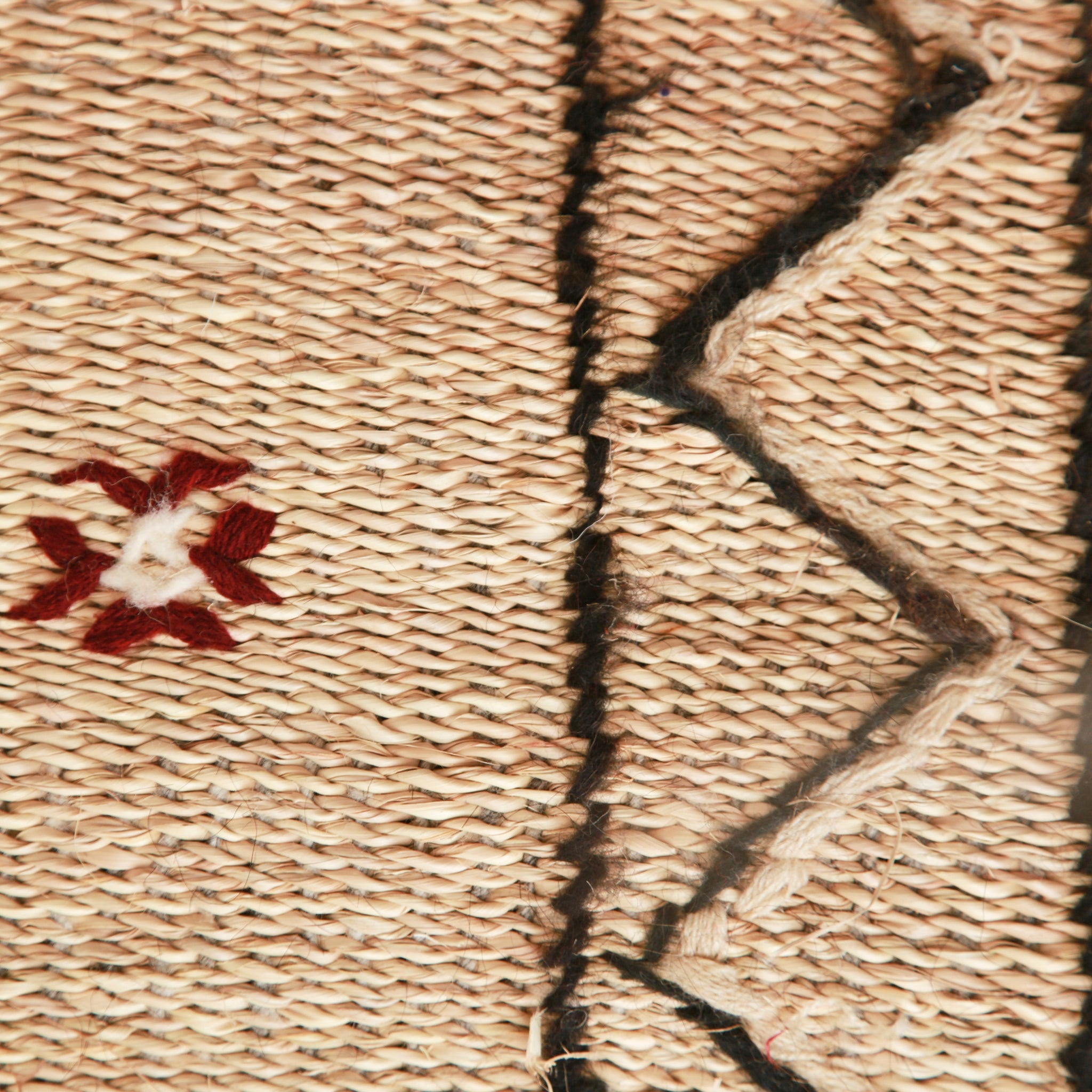 dettaglio del ricamo di una stuoia hassira in paglia di piccole dimensioni con lana ricamata nera e qualche simbolo rosso