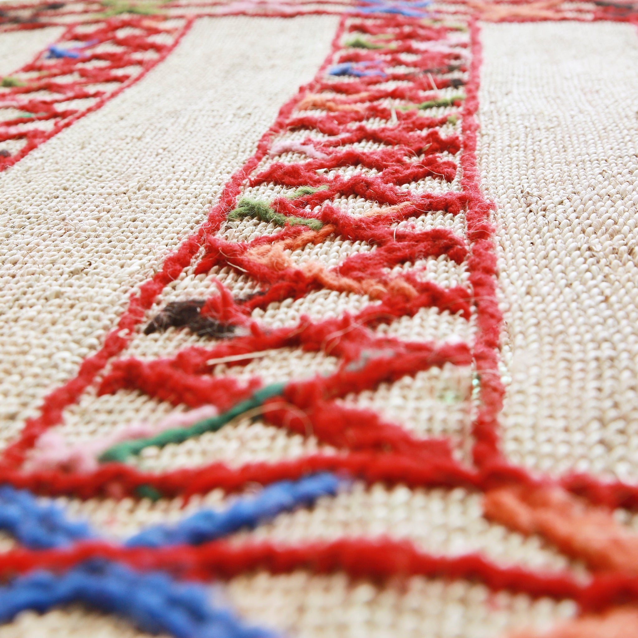 dettaglio di una stuoia hassira in paglia di palma con ricami in lana rossa blu verde e rosa