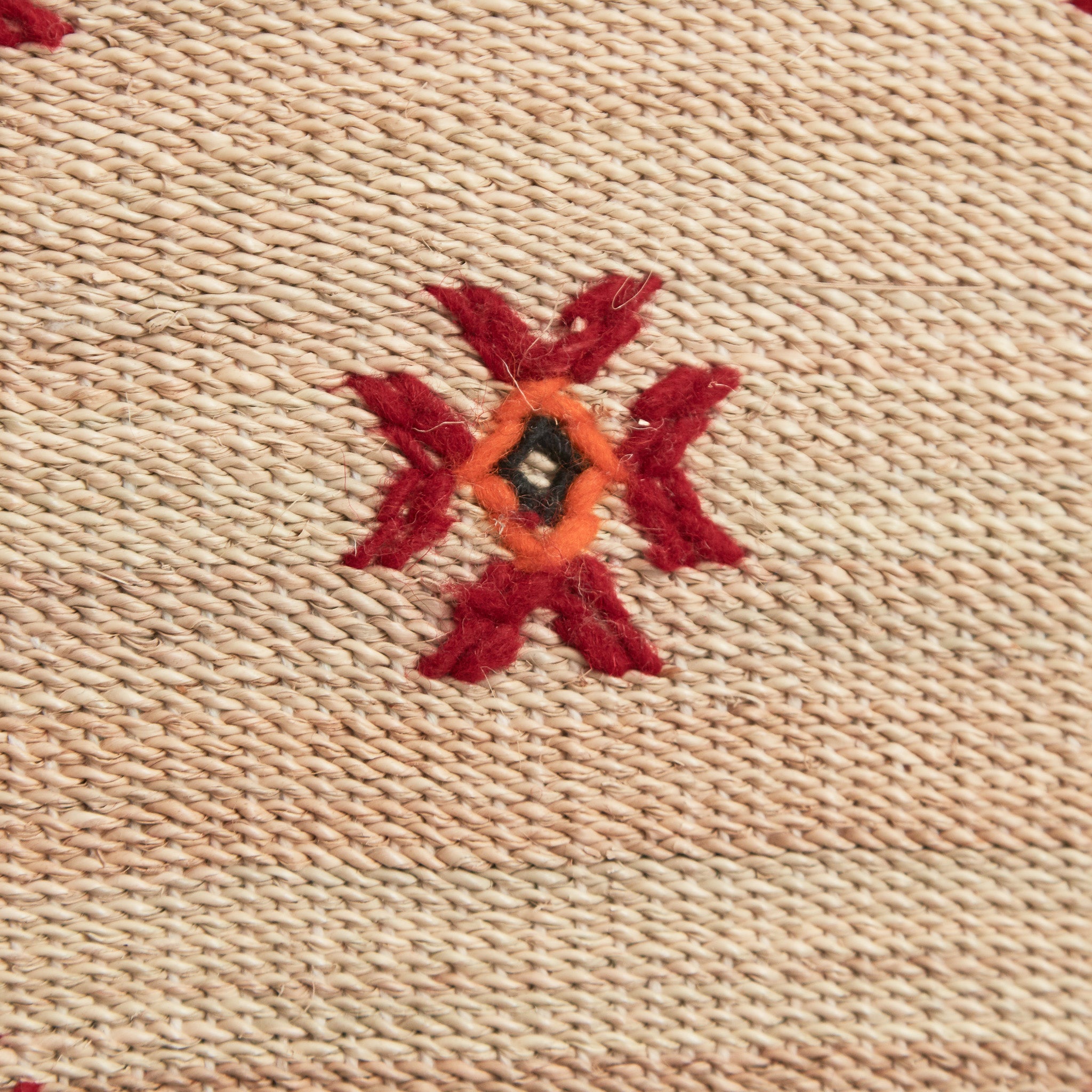 dettaglio del ricamo in lana rossa arancione e nera di una stuoia tappeto in paglia hassira media in paglia di palma e ricami in lana