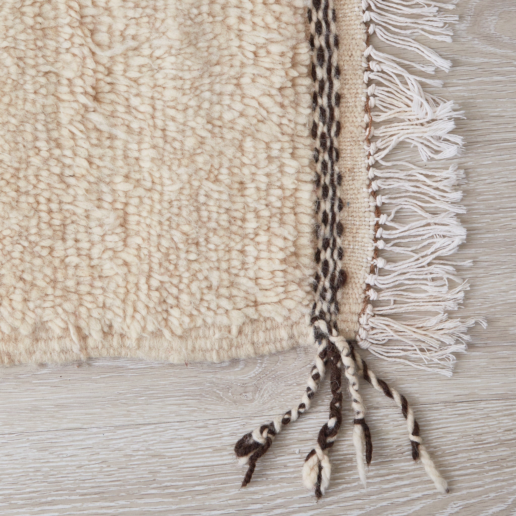 tappeto azilal in morbida lana a pelo corto con disegno astratto su base bianca dettaglio frangia e lato corto con tessitura scura