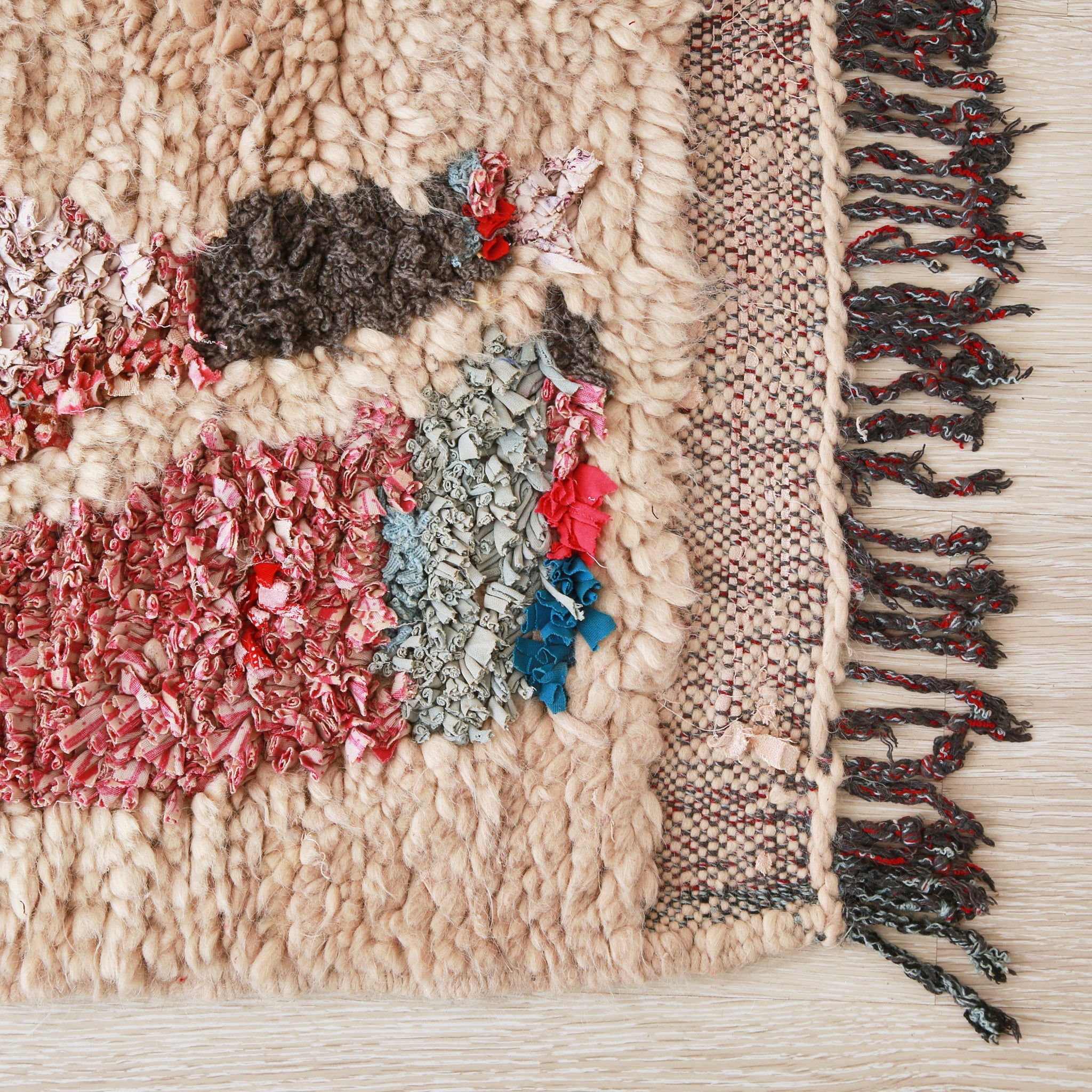 angolo di un tappeto con lana bianca e stracci di tessuto e frangia di colore scuro