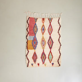 tappeto azilal piccolo con tre file di rombi colorati su base in lana bianca disteso