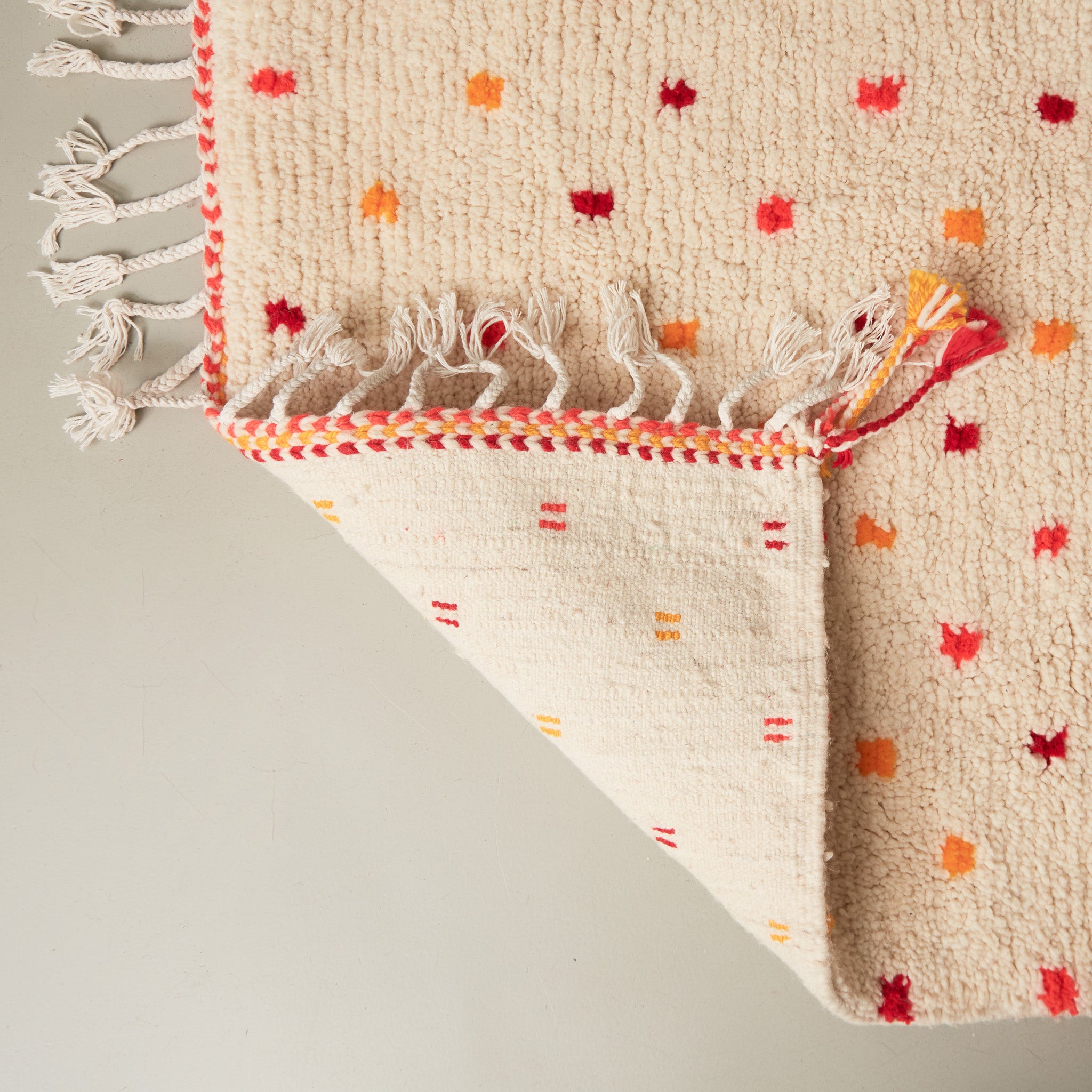 dettaglio del retro di un tappeto azilal in lana chiara con pois gialli rossi arancioni