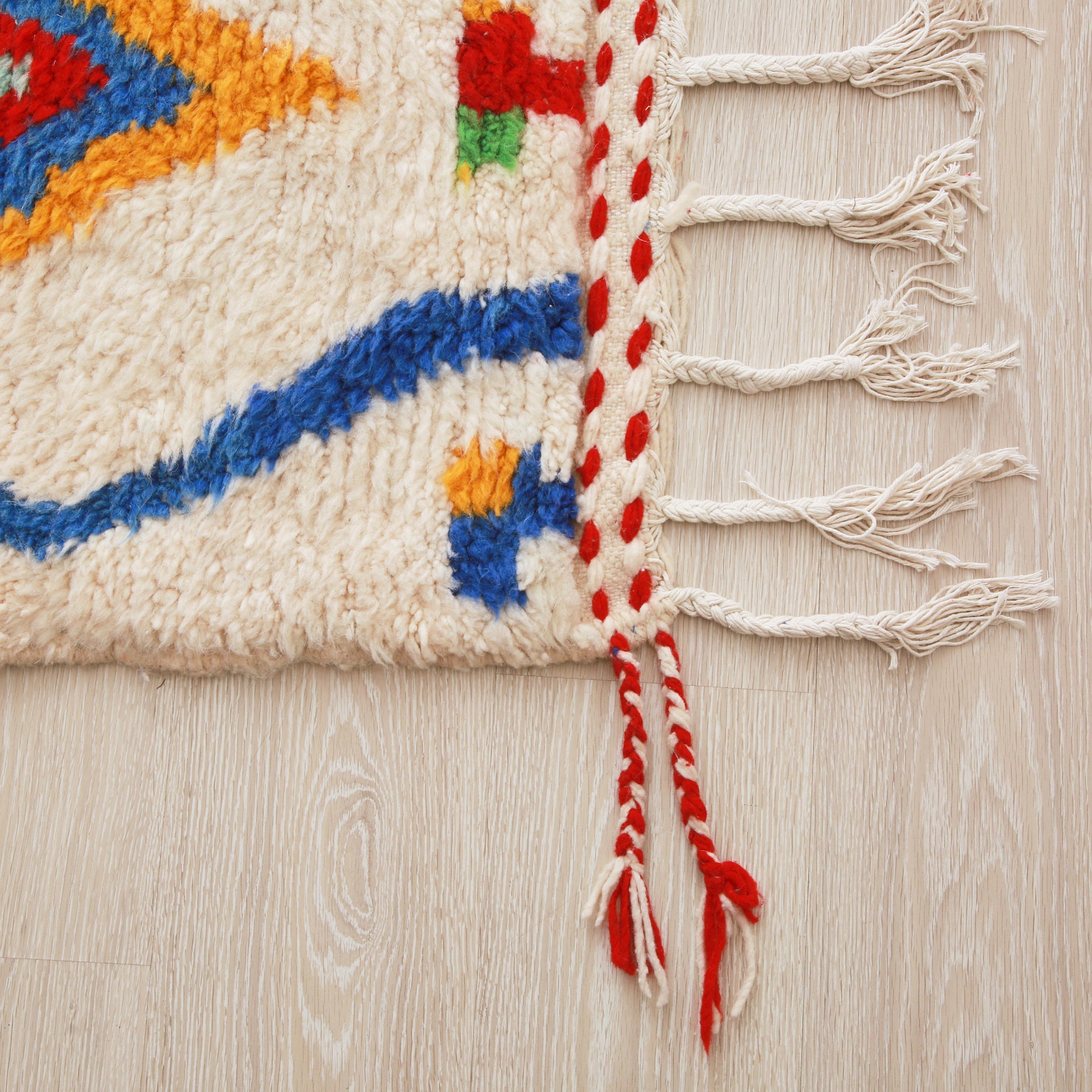 angolo di un tappeto azilal con una doppia frangia, una bianca e una bianca e rossa