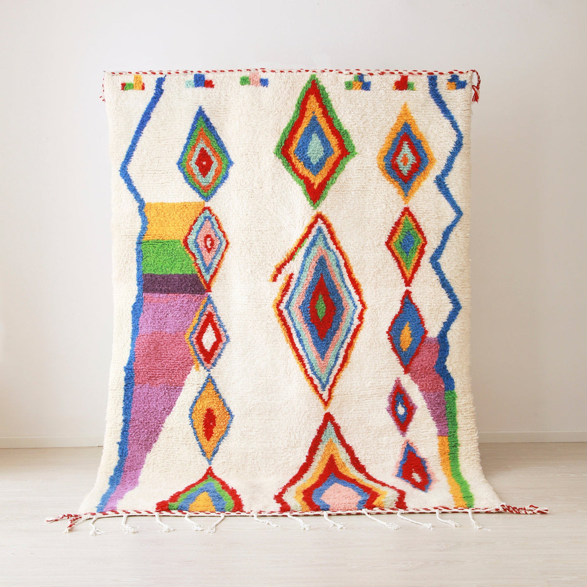 tappeto azilal appeso realizzato con lana bianca e rombi di diverse dimensioni dai colori brillanti