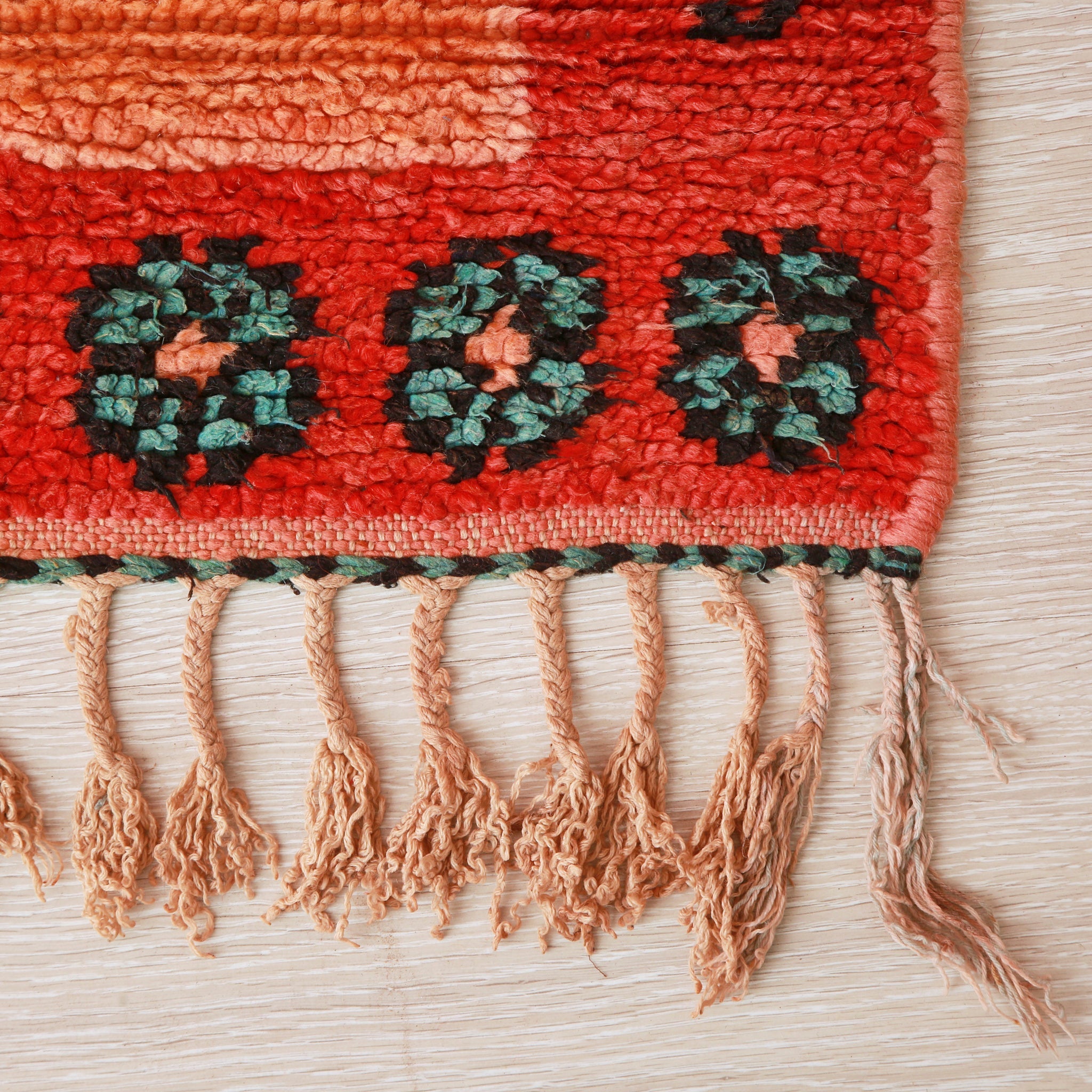 angolo di un tappeto azilal con fiori verdi su base rossa