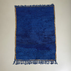 tappeto beni mguild blu con bordo zafferano e frangia blu disteso su pavimento