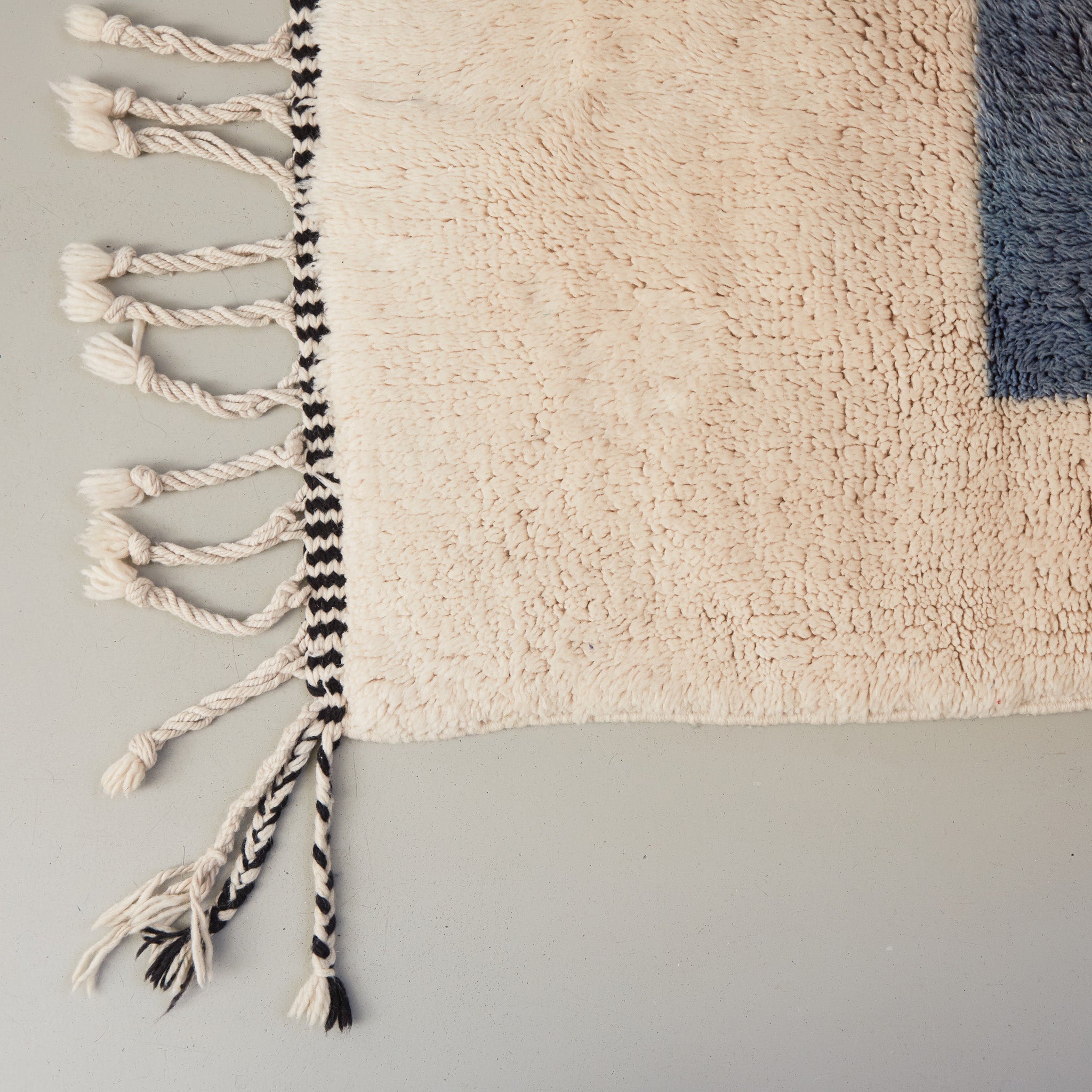 dettaglio della frangia bianca e nera e della lana bianca e azzurra di un tappeto beni mrirt