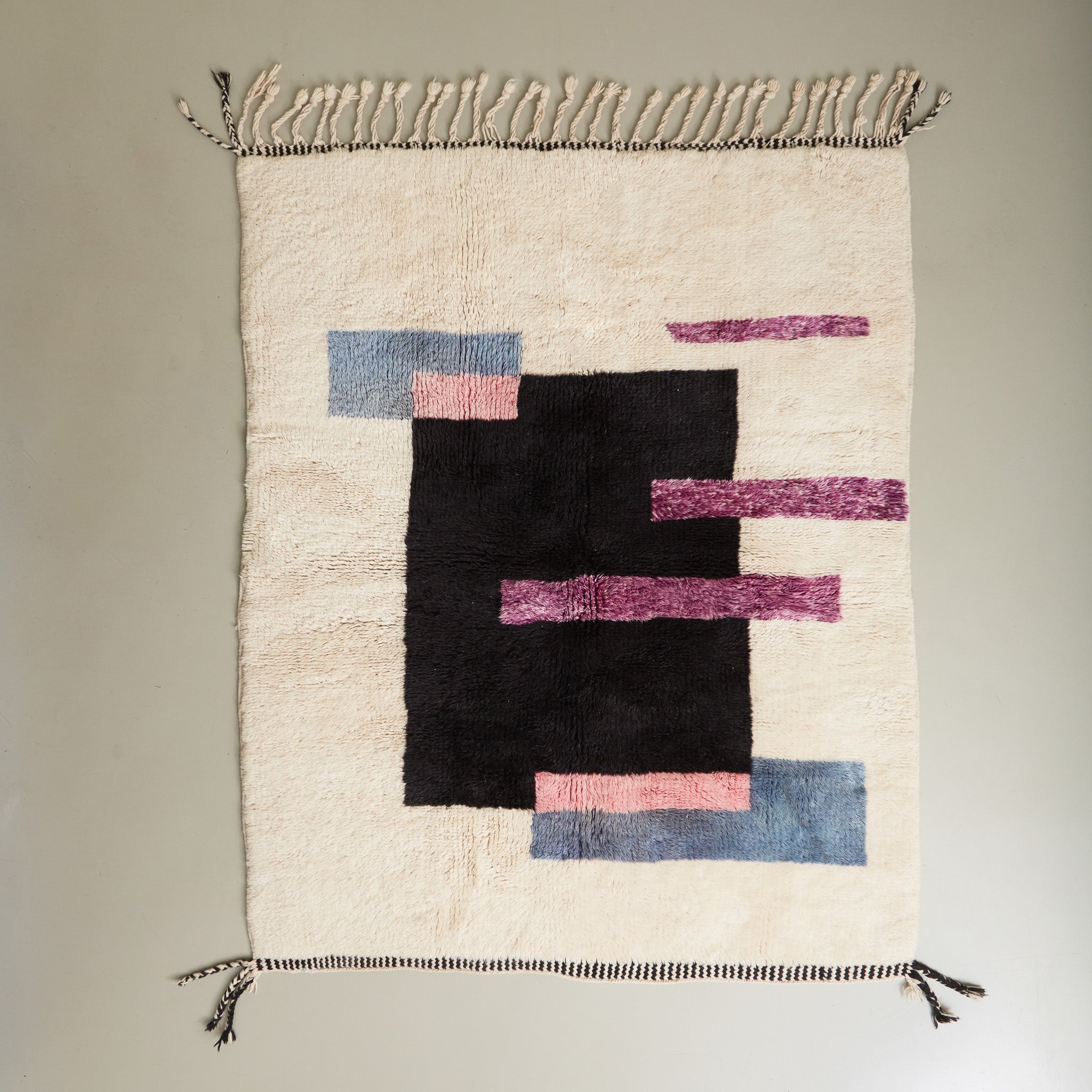 tappeto beni mrirt con design contemporaneo a rettangoli colorati neri viola rosa e azzurro su base in lana bianca disteso 