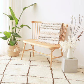 Foto ambinetata di un tappeto beni mrirt bianco con un pianta, una panchina in legno e una composizione di fiori