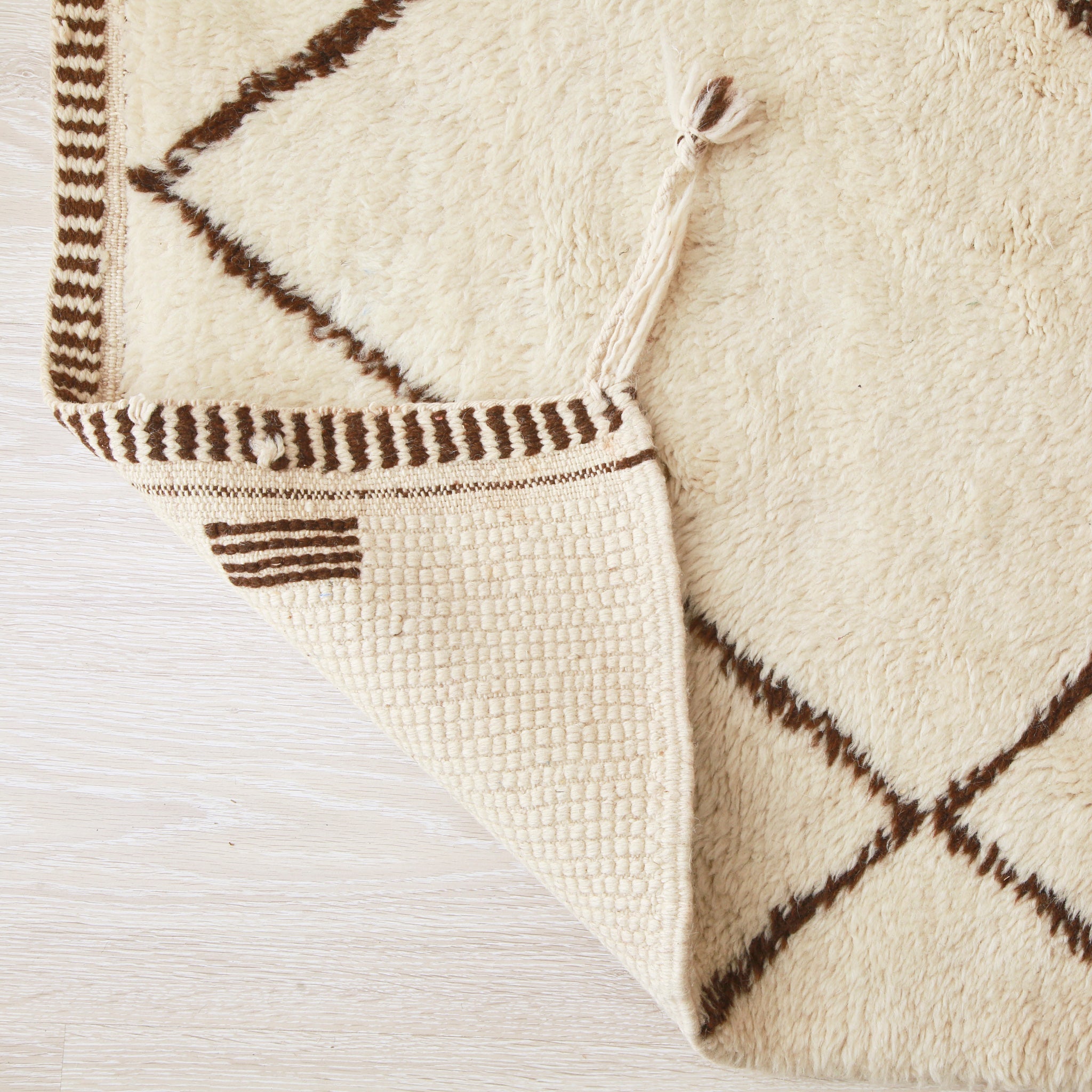 retro dell'angolo di un tappeto beni mrirt bianco per ammirare la precisione e la vicinanza dei nodi nonché la cura nella finitura dei lati