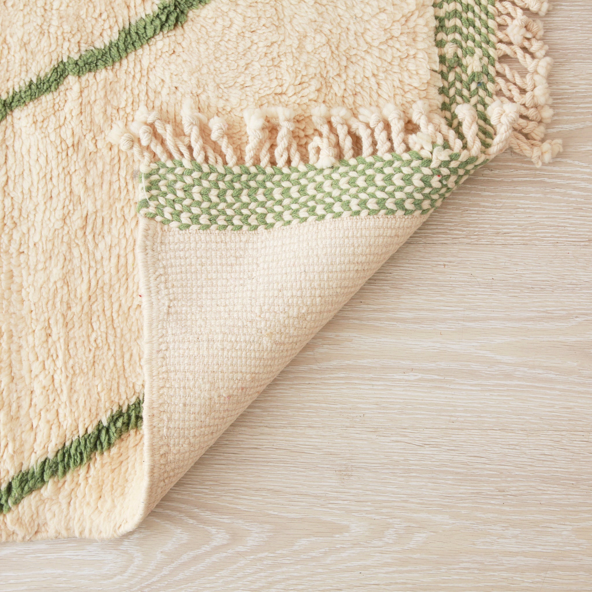 retro di un tappeto beni mrirt con lana bianca  e alcune righe verde. Il bordo della frangia è bianco e verde