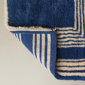 dettaglio del retro e della frangia corta di un tappeto beni mrirt  piccolo realizzato con lana blu e disegni geometrici bianchi