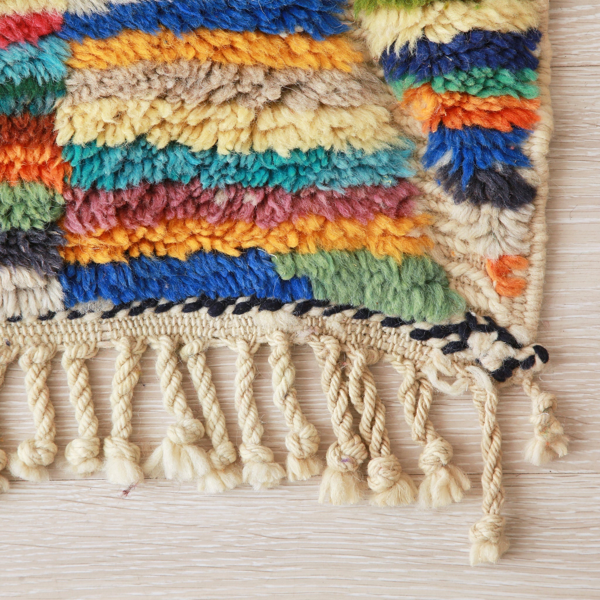 angolo di un tappeto beni mrirt colorato, la frangia è annodata in grosse trecce