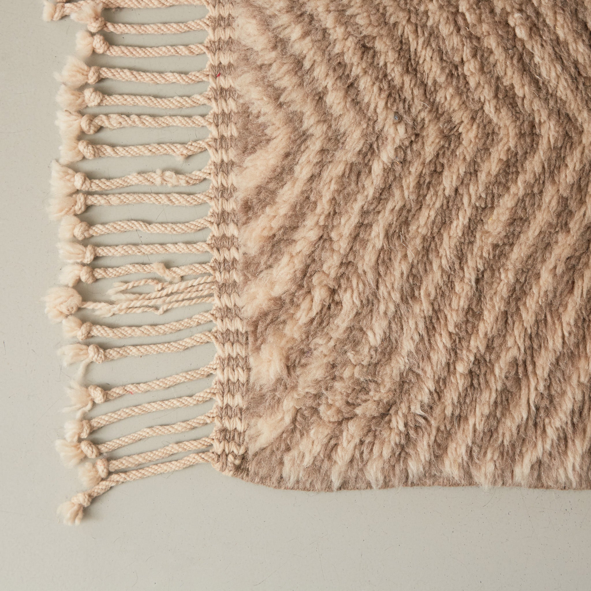 dettaglio dell'angolo e della frangia ben lavorata di un tappeto beni mrirt design contemporaneo color tortora bianco