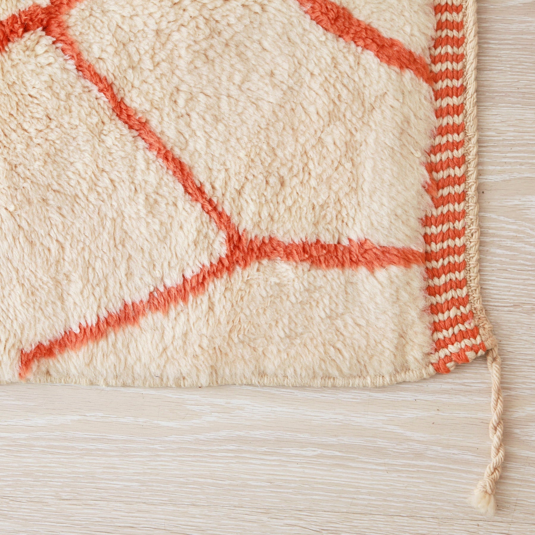 Dettaglio dell'angolo del tappeto senza frangia, ma con il bordo arancione