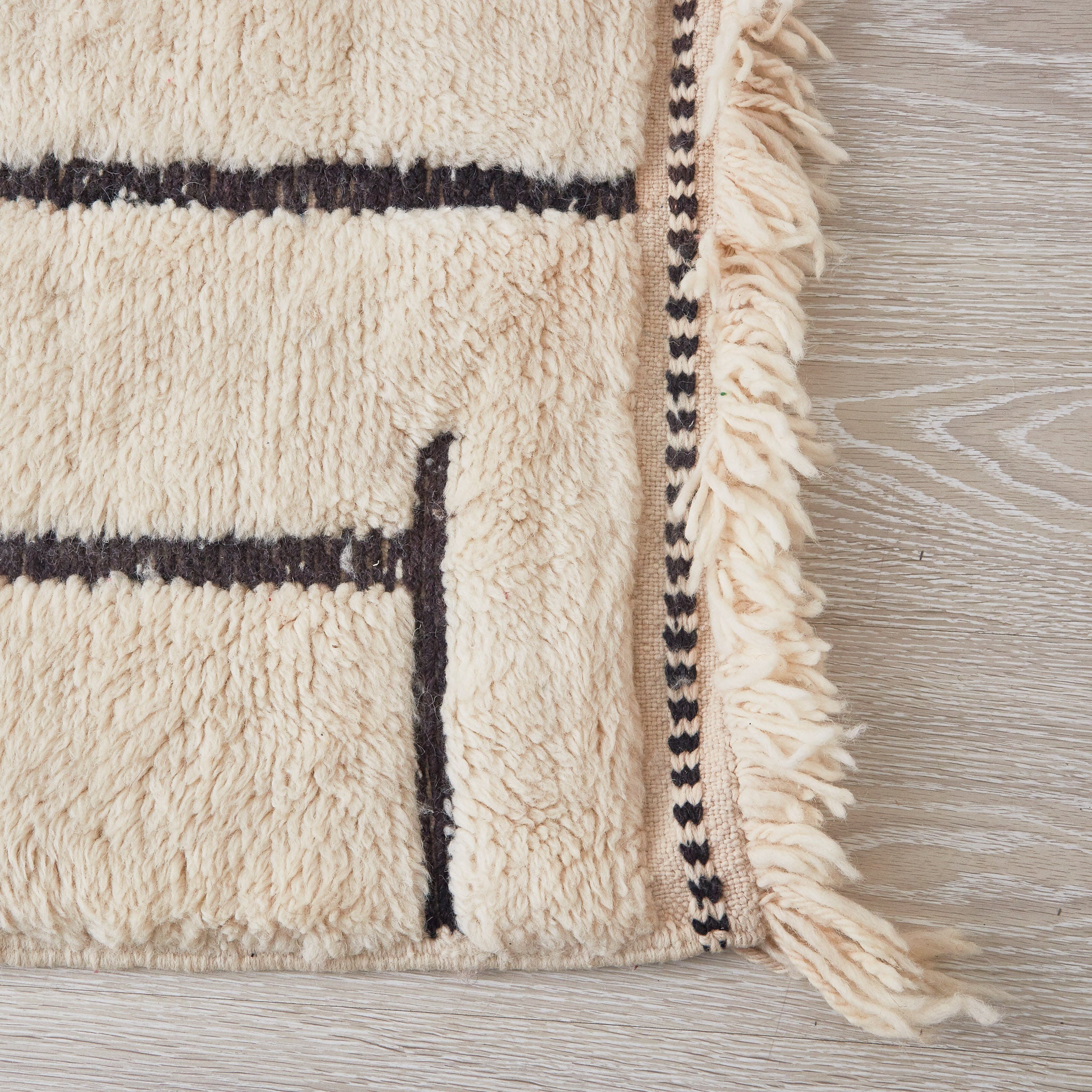 tappeto beni mrirt in morbida lana a pelo lungo con righe nere su base bianca dettaglio frangia