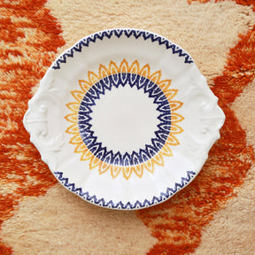 Dettaglio di un tappeto beni mrirt cona appoggiato sopra un piatto  con dei disegni gialli e arancioni