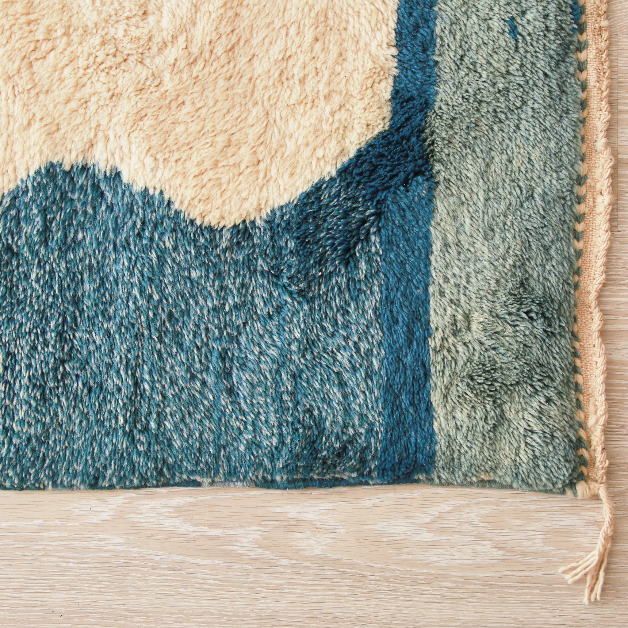 Angolo di un tappeto beni mrirt per evidenziare la qualità della lana utilizzata e le sfumature del bordo in varie tonalià di blu e azzurro