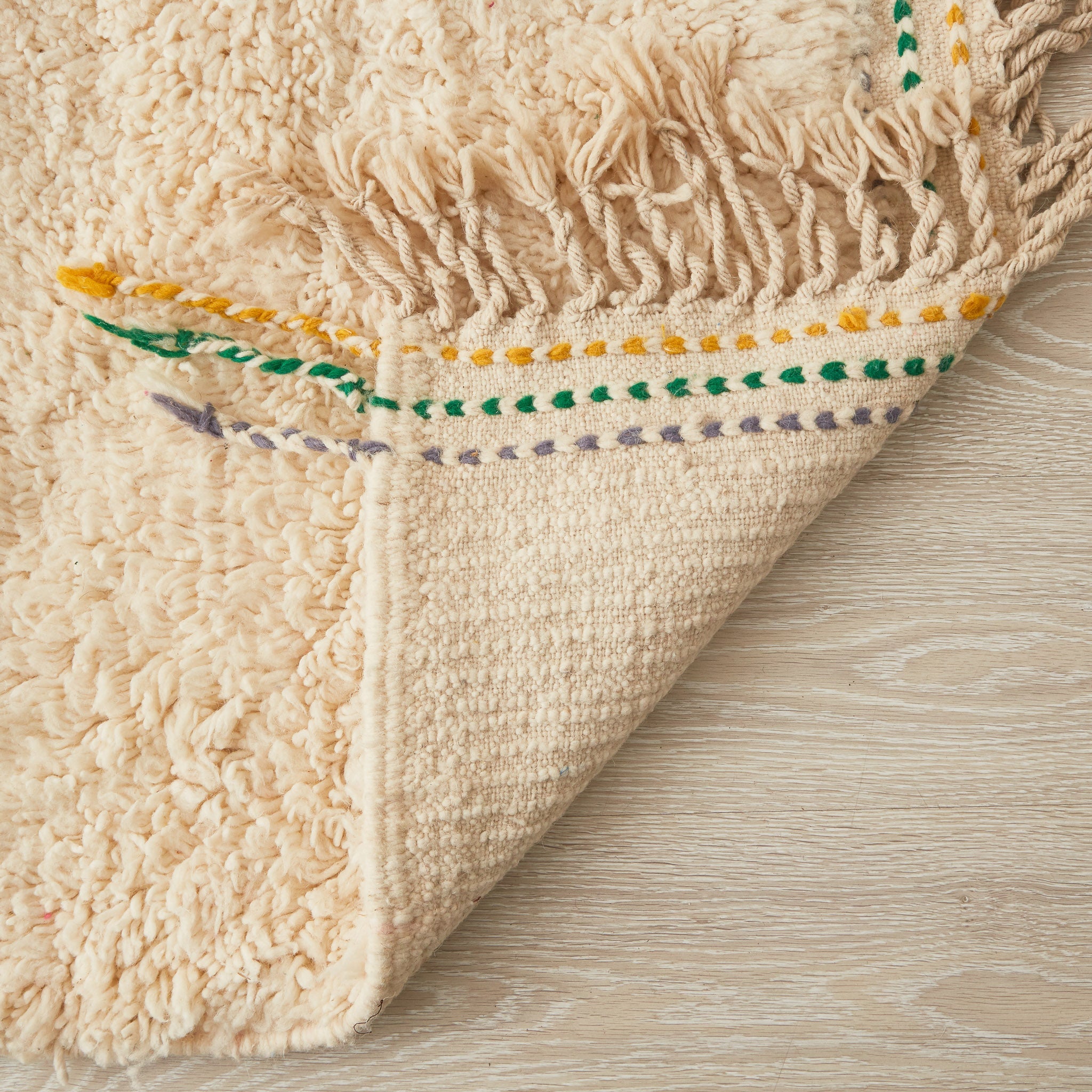 tappeto beni ourain con morbido pelo lungo di colore bianco con linee e frange di diversi colori dettaglio del retro