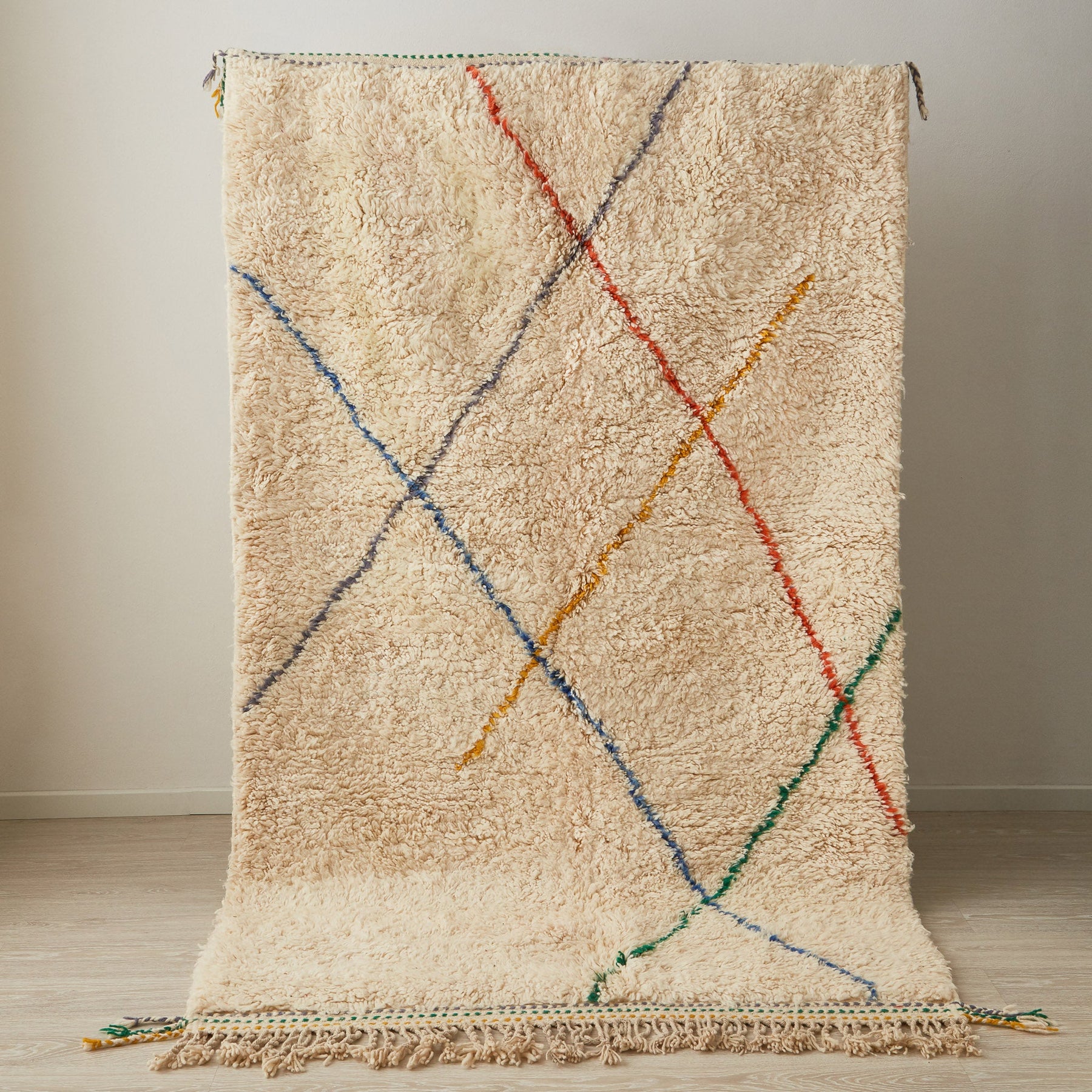 tappeto beni ourain con morbido pelo lungo di colore bianco con linee e frange di diversi colori in posizione verticale