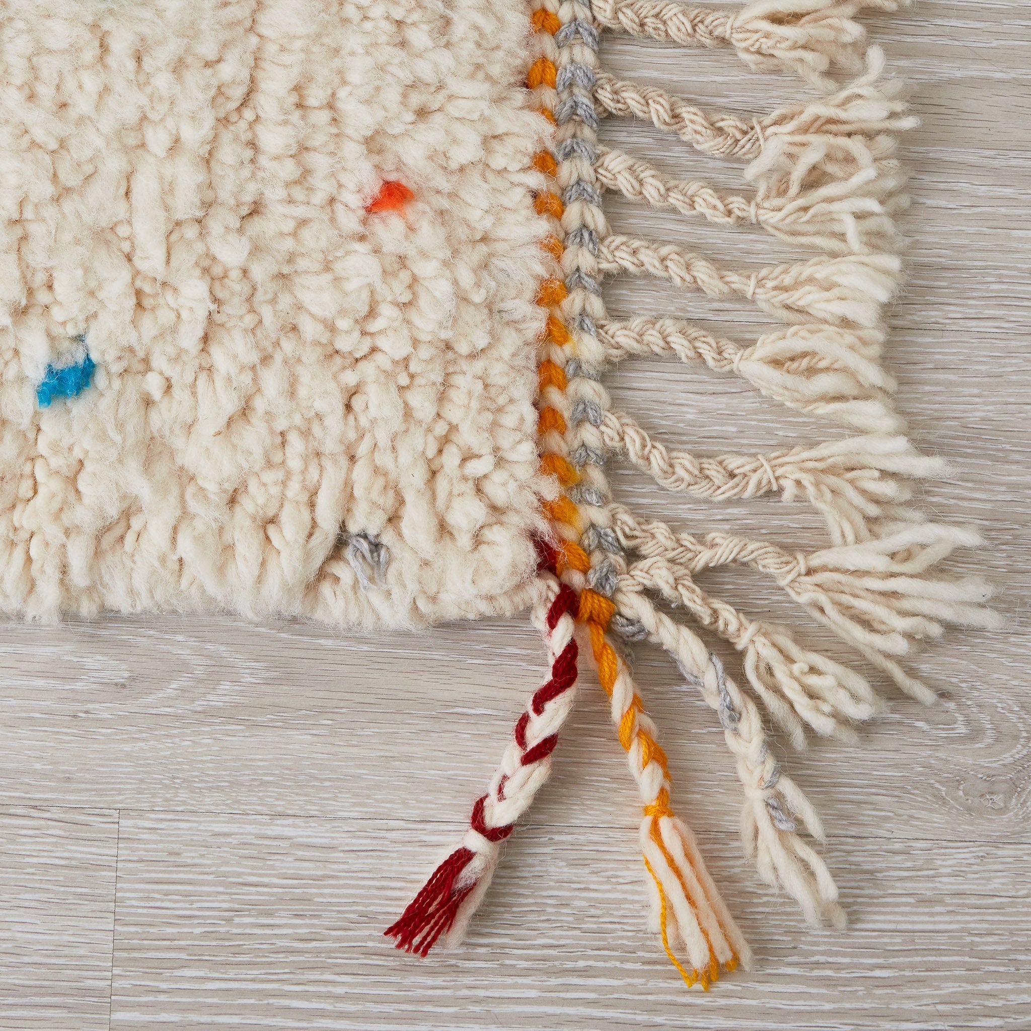 Tappeto beni ourain per cameretta con pois di diversi colori e frange di due colori su base bianca dettaglio delle tre frange