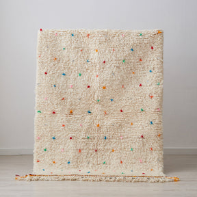 Tappeto beni ourain per cameretta con pois di diversi colori e frange di due colori su base bianca posizionato in verticale