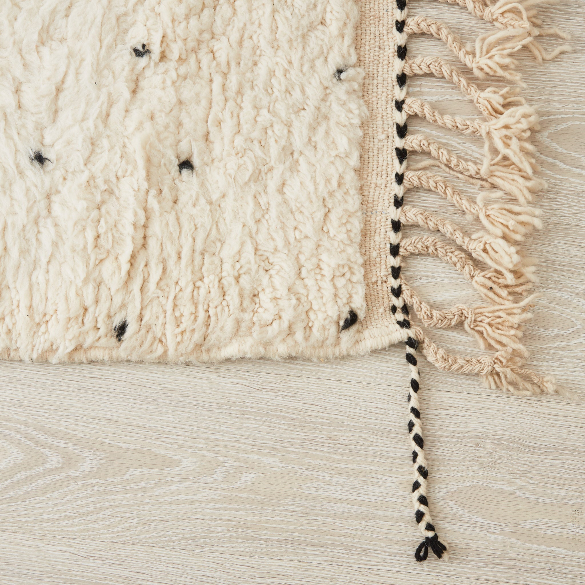 tappeto beni ourain con morbido pelo lungo pois neri e frangia bianca e nera dettaglio dell'angolo con due tipi di frange