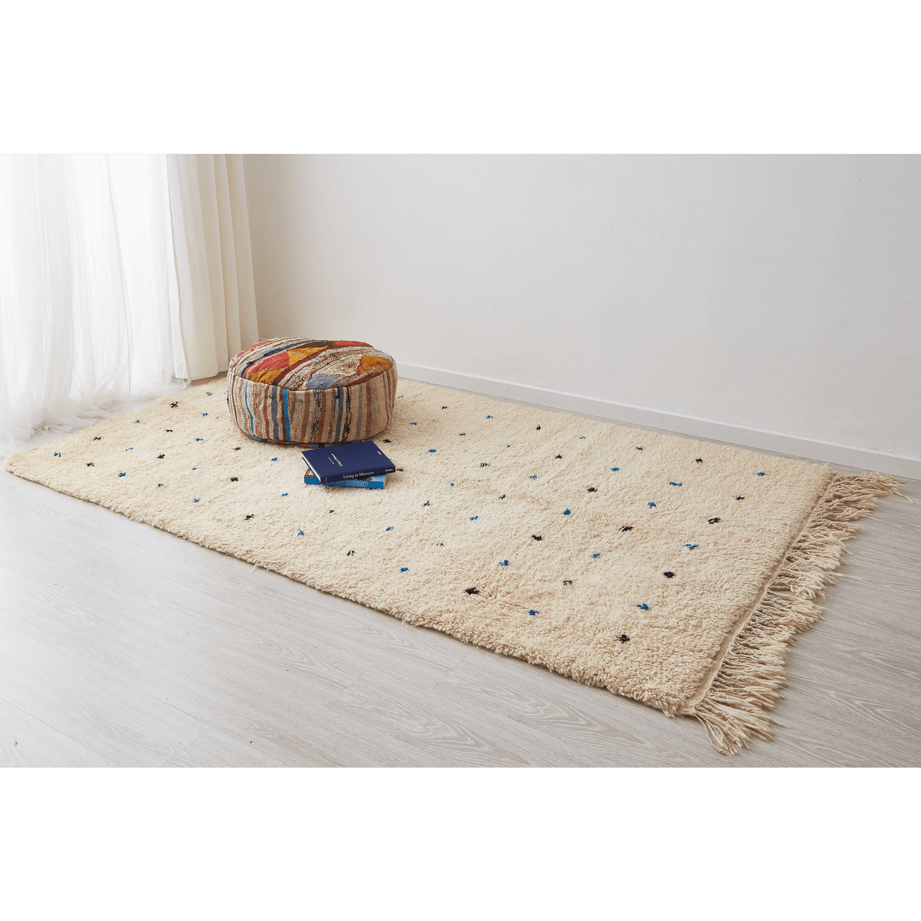 tappeto beni ourain in morbida lana bianca con pois neri e azzurri disteso sul pavimento