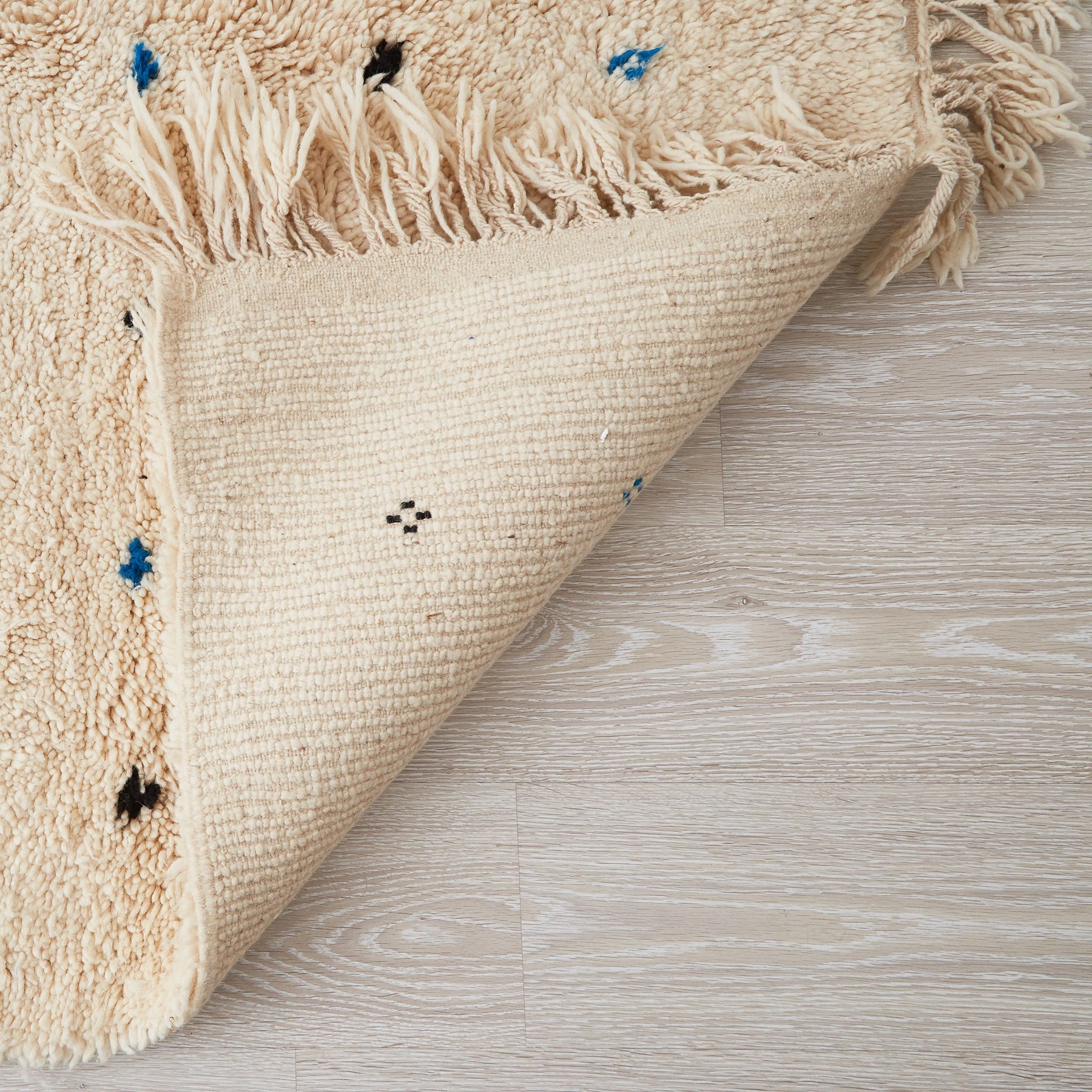 tappeto beni ourain in morbida lana bianca con pois neri e azzurri dettaglio del retro