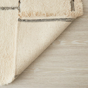 tappeto beni ourain con rettangoli neri su base bianca  lato corto nero e frangia bianca dettaglio del retro