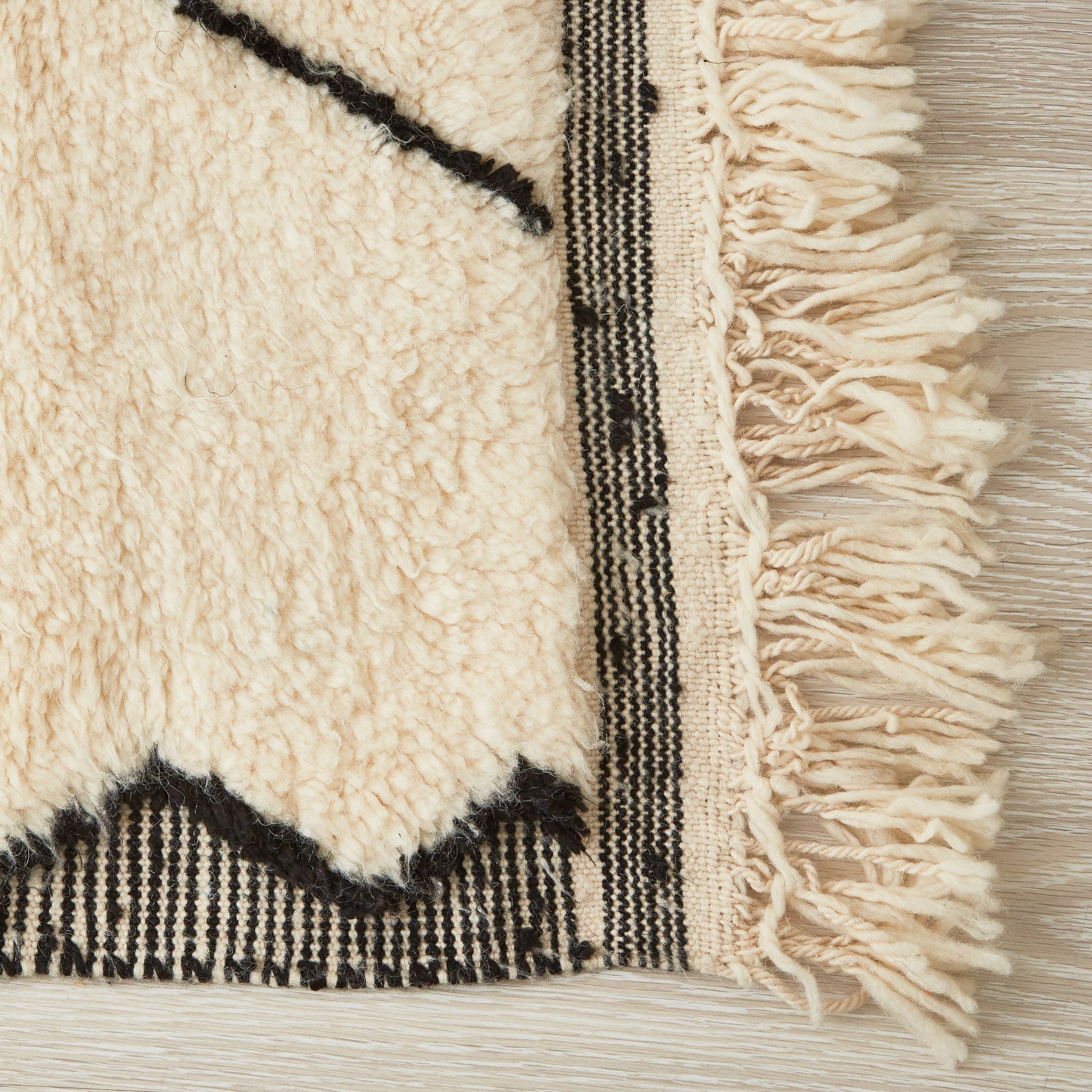 tappeto beni ourain in tinta unita con rombi e bordi neri dettaglio dell'angolo e della frangia