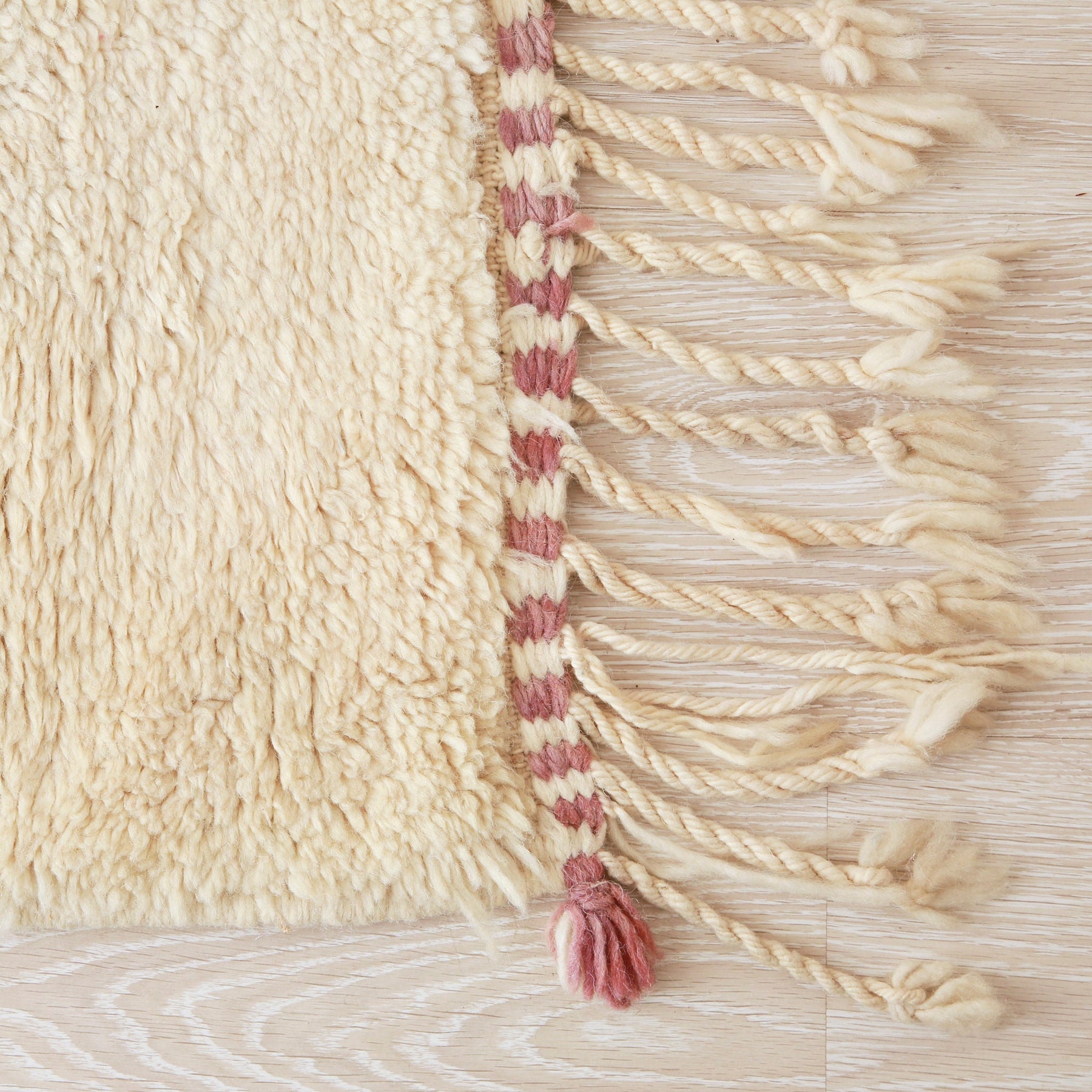angolo di un tappeto beni ourain con una luga frangia bianca e un piccolo ciuffo lilla che esce dalla punta