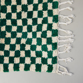dettaglio dell'angolo e della frangia di un tappeto beni ourain a scacchiera bianca verde 